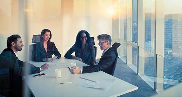 People gathered around conference room table with natural daylight